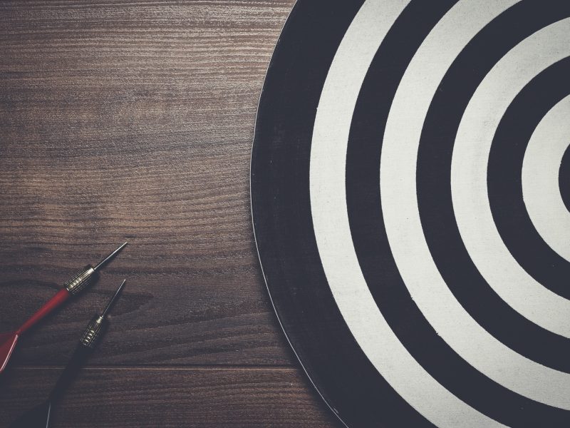 two darts and target on wooden background